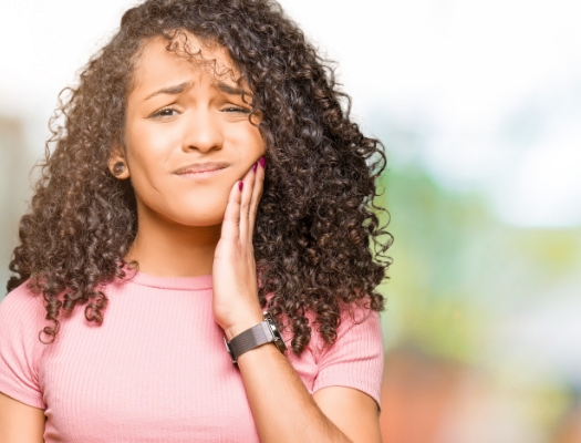 Woman with pink shirt rubbing her jaw