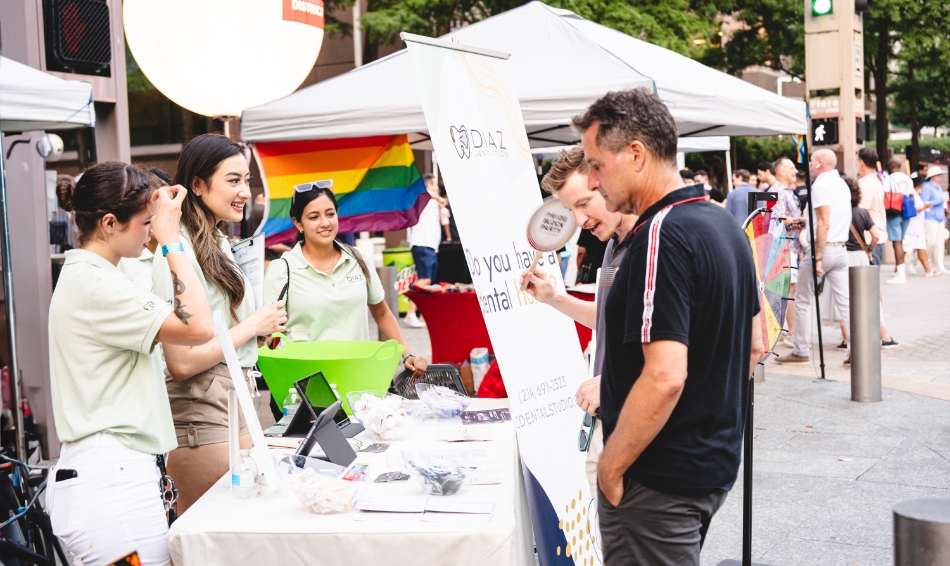 Dental team members talking to two men at a community event