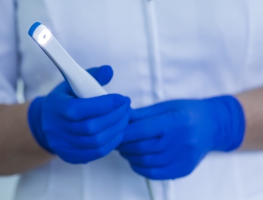 Gloved hands holding an intraoral camera