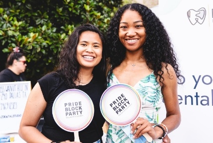 Two women holding signs that say Pride Block Party