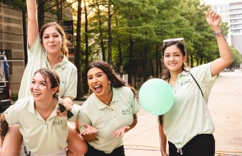 Four women smiling and walking down street