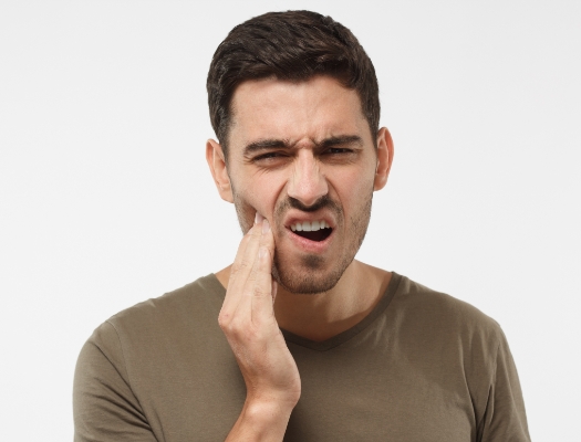 Close up of man in green shirt with tooth pain