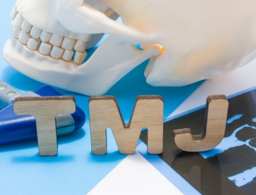 Cardboard letters spelling out TMJ in front of skull